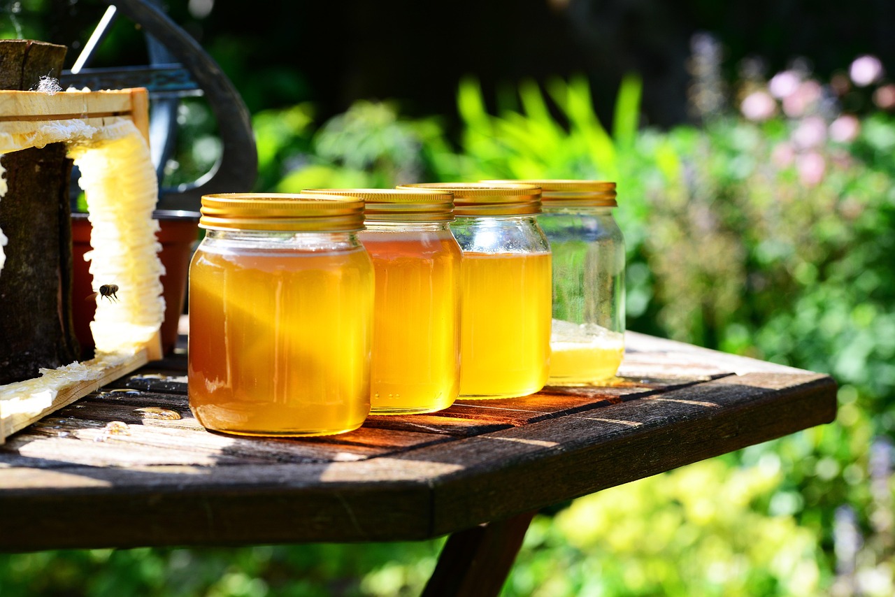Jars of golden honey arranged on an outdoor wooden table